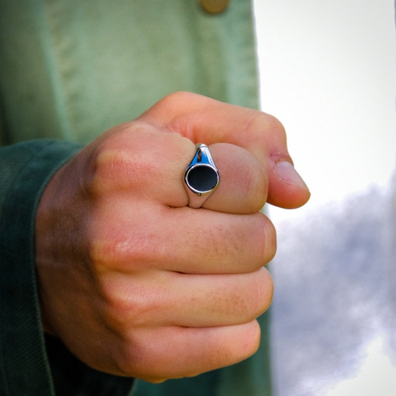 May include: A silver signet ring with a black oval stone.
