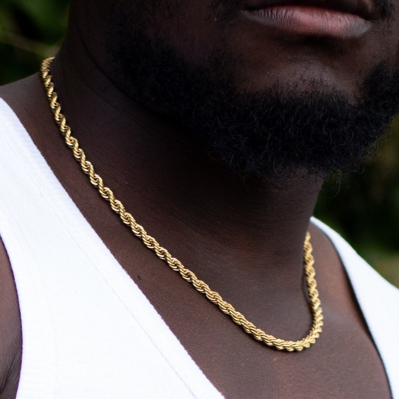 Puede incluir: Un collar de cadena de cuerda dorada alrededor del cuello de una persona.