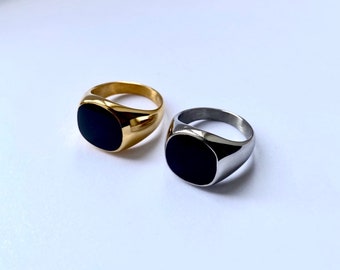 Könnte beinhalten: Zwei Siegelringe mit schwarzen ovalen Einsätzen. Ein Ring ist golden, der andere silbern.