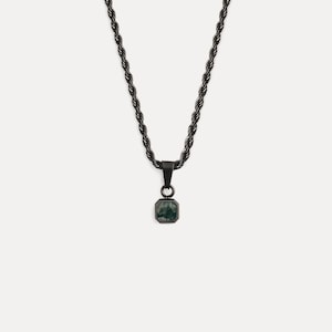 May include: A black necklace with a square pendant. The pendant features a dark green stone set in a black metal frame. The chain has a rope-like design. The necklace is displayed against a white background.