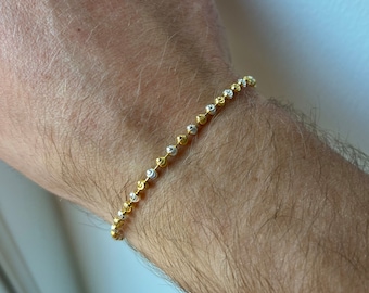 May include: A gold and silver two-tone bracelet with a beaded chain design.