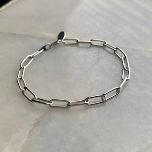 May include: A silver chain bracelet with a simple, linked design. The bracelet is made of oval-shaped links.