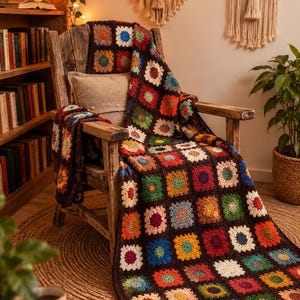 Puede incluir: Una manta de ganchillo hecha a mano con un patrón repetitivo de coloridos cuadrados granny unidos por hilo marrón oscuro. La manta muestra una variedad de tonos vibrantes que incluyen rojo, azul, verde, amarillo y naranja sobre una silla.