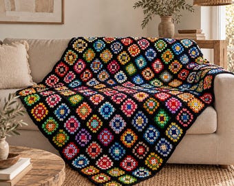 May include: A crochet blanket featuring a repeating pattern of multi-colored granny squares joined by black yarn. Each square contains a vibrant center of red, yellow, blue, green, pink, or orange, framed by a consistent black border throughout.