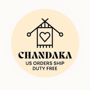 May include: A circular logo on a pale yellow background featuring a black line art icon of two crossed knitting needles and a rectangular piece of fabric with a heart shape in the center. Below the icon, the text CHANDAKA is printed in black.