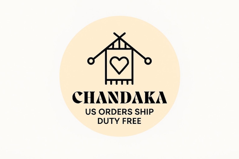 May include: A circular logo on a pale yellow background featuring a black line art icon of two crossed knitting needles and a rectangular piece of fabric with a heart shape in the center. Below the icon, the text CHANDAKA is printed in black.