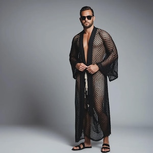 May include: A black, open-front mesh robe with long sleeves. The robe is floor-length and has a tie closure at the waist. The model is wearing black sunglasses and sandals.