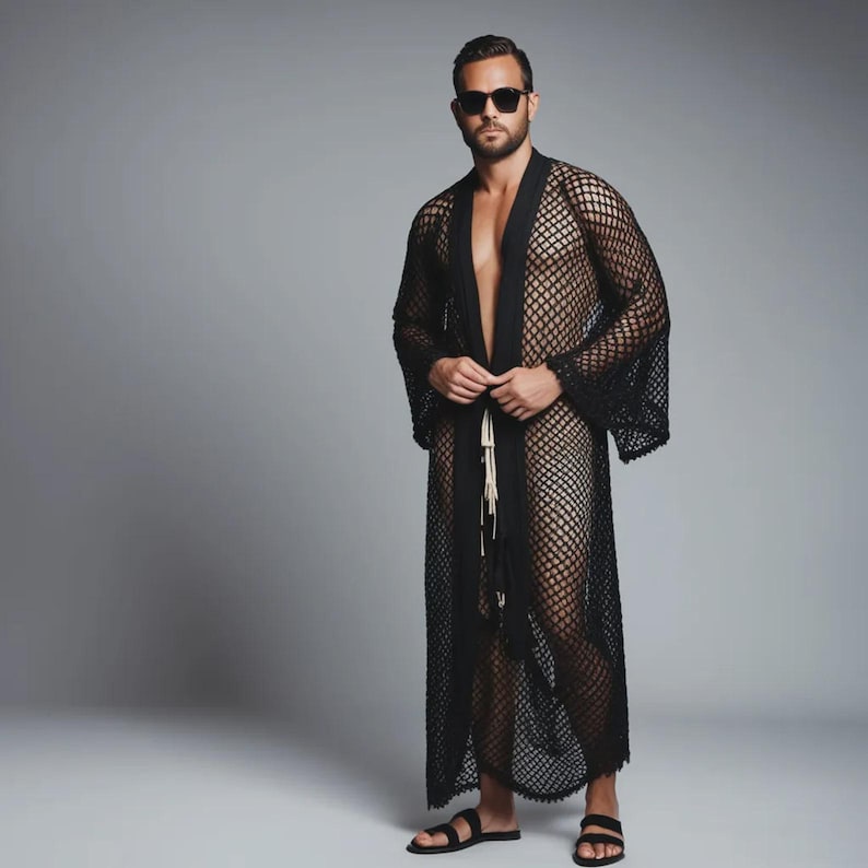 May include: A black, open-front mesh robe with long sleeves. The robe is floor-length and has a tie closure at the waist. The model is wearing black sunglasses and sandals.