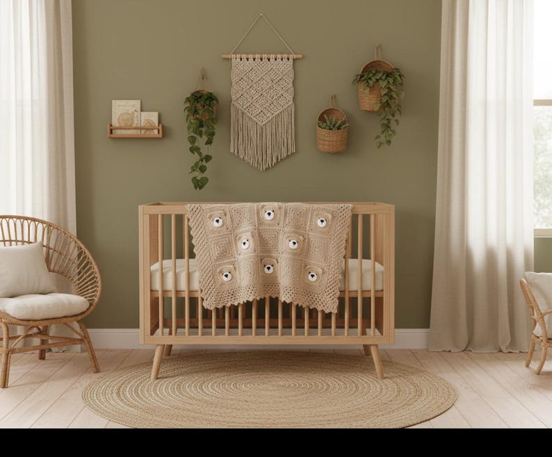 May include: A light beige crochet baby blanket featuring a repeating pattern of square motifs, each centered with a small, three-dimensional stuffed bear face with dark eyes and a nose, draped over a wooden crib with vertical slats and tapered legs.
