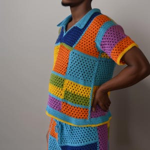 May include: A colourful crochet top and trousers set in a patchwork design with blue, orange, yellow, green, and purple squares.