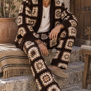 Puede incluir: Un conjunto de c&aacute;rdigan y pantal&oacute;n de ganchillo con un patr&oacute;n de cuadrados granny en tonos marr&oacute;n, beige y crema. El c&aacute;rdigan tiene cuello y pu&ntilde;os de canal&eacute; en marr&oacute;n oscuro, a juego con el pantal&oacute;n de corte recto.