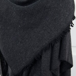 May include: A dark gray fringed scarf made of a soft, textured fabric.