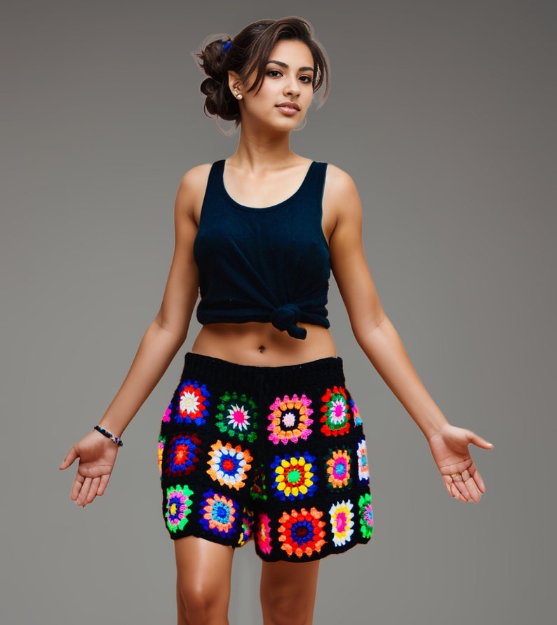May include: Black crochet shorts with colorful square patterns. The shorts feature a high waist and a vibrant mix of red, yellow, green, blue, and pink squares. The model is wearing a dark blue tank top.