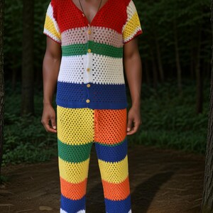 May include: A person wearing a multi-coloured crocheted shirt and trousers. The shirt and trousers are made of a thick yarn and have a striped pattern. The colours of the stripes are red, pink, green, white, blue, yellow, and orange.