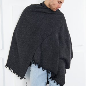 May include: A person wearing a dark gray shawl with a fringed edge and light blue jeans.