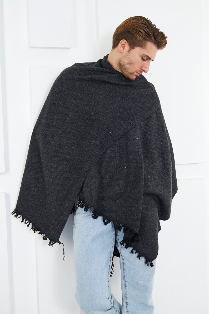 May include: A person wearing a dark gray shawl with a fringed edge and light blue jeans.