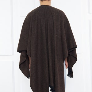 May include: A brown poncho with a fringed hem. The poncho is made of a soft, textured fabric.