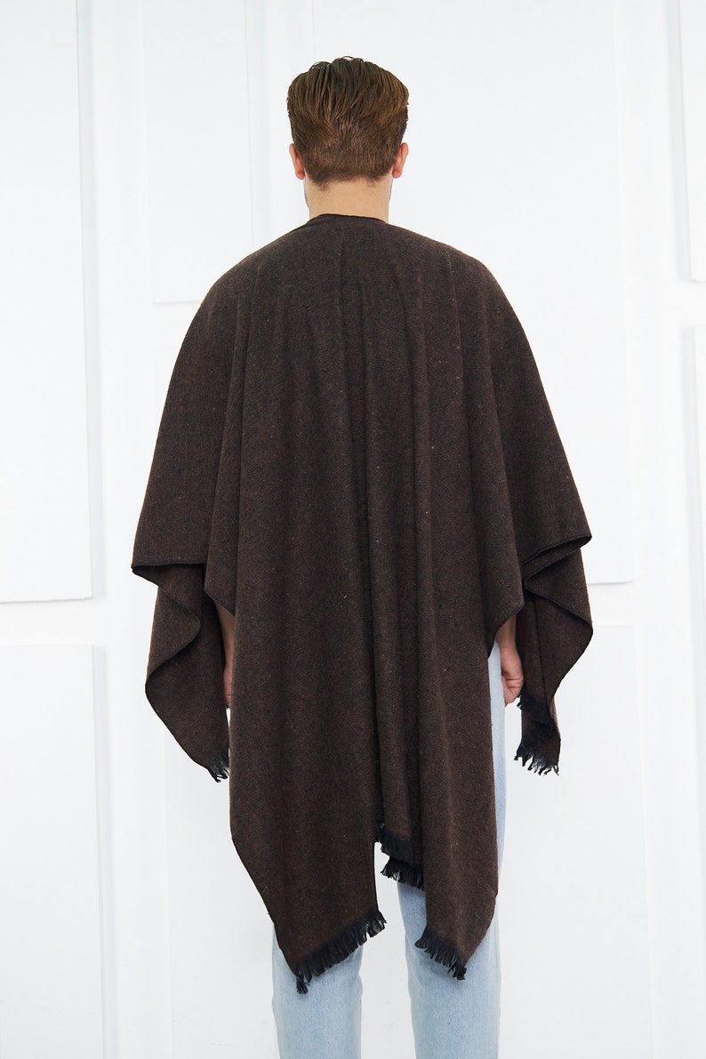 May include: A brown poncho with a fringed hem. The poncho is made of a soft, textured fabric.