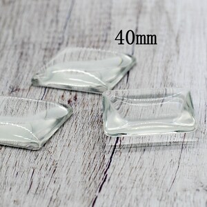 May include: Three clear glass square dishes on a wooden surface. The largest dish is labeled "40mm".