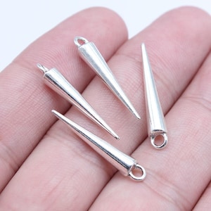 May include: Four silver-colored cone-shaped charms with a loop at the top for jewelry making. The charms are tapered and have a shiny, metallic finish. They are displayed against a neutral background.
