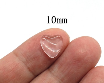 May include: A clear, heart-shaped glass bead, approximately 10mm in size. The bead is transparent with subtle internal lines, resting on a fingertip. The text "10mm" is displayed in black.