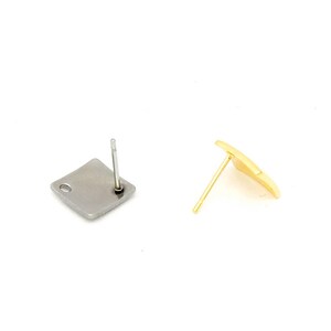 May include: Two earring posts, one with a silver square and one with a gold square.
