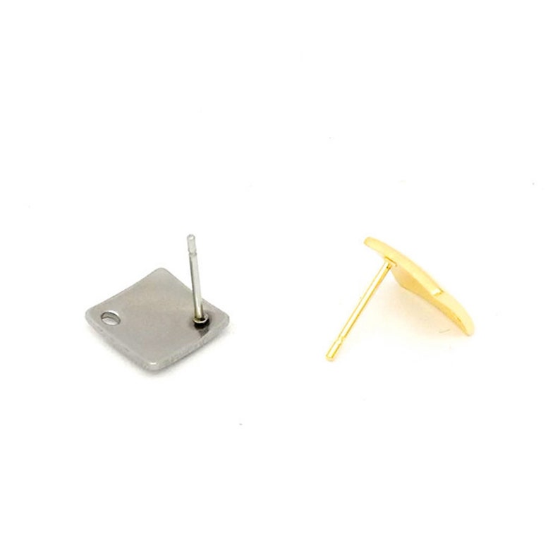 May include: Two earring posts, one with a silver square and one with a gold square.