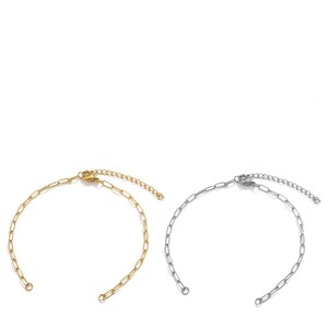 May include: Two delicate chain bracelets. One is gold-toned, the other is silver-toned. Both have a simple, elongated link design and an adjustable chain closure. The bracelets are displayed against a white background, highlighting their minimalist style.