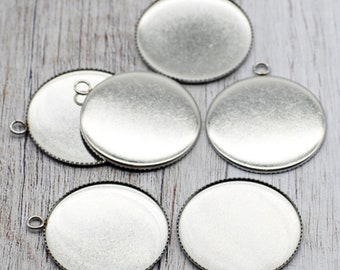 May include: Five silver-toned metal round pendant trays with a beveled edge and a loop at the top for hanging.