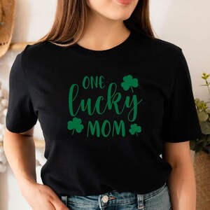 May include: Black t-shirt with the text "One lucky mom" in green cursive lettering and shamrock designs.
