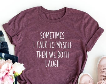 May include: Heather maroon t-shirt with the text "SOMETIMES I TALK TO MYSELF THEN WE BOTH LAUGH". The shirt is styled with rolled-up blue jeans, pink sneakers, and a bouquet of flowers.