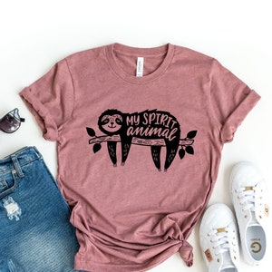 May include: Heather mauve t-shirt with a black graphic of a sloth on a branch with the text "My spirit animal".