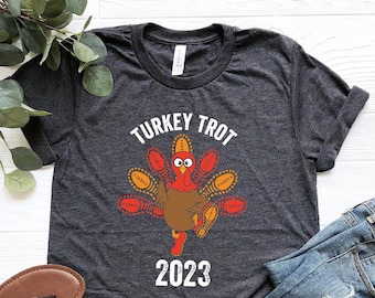 May include: Heather dark grey t-shirt with a graphic of a turkey running with the text "Turkey Trot 2023".