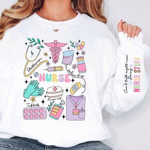 May include: White sweatshirt with a colorful graphic of medical tools and the word "NURSE". The design includes a stethoscope, pills, a nurse cap, and the text "Can't talk right now Doing NURSE STUFF" on the sleeve.