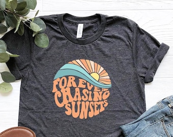 May include: Heather dark grey t-shirt with a graphic of a sunset and waves with the text "Forever Chasing Sunsets".