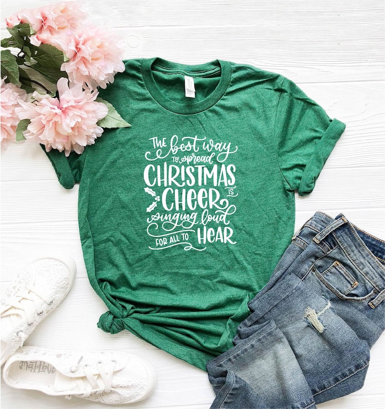 May include: Green t-shirt with white text that reads "The best way to spread Christmas Cheer is singing loud for all to hear".