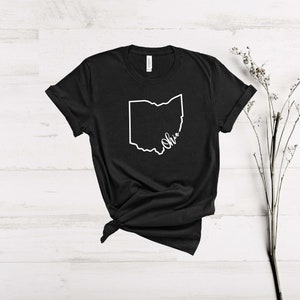 May include: Black t-shirt with a white outline of the state of Ohio and the word "Ohio" written in cursive.