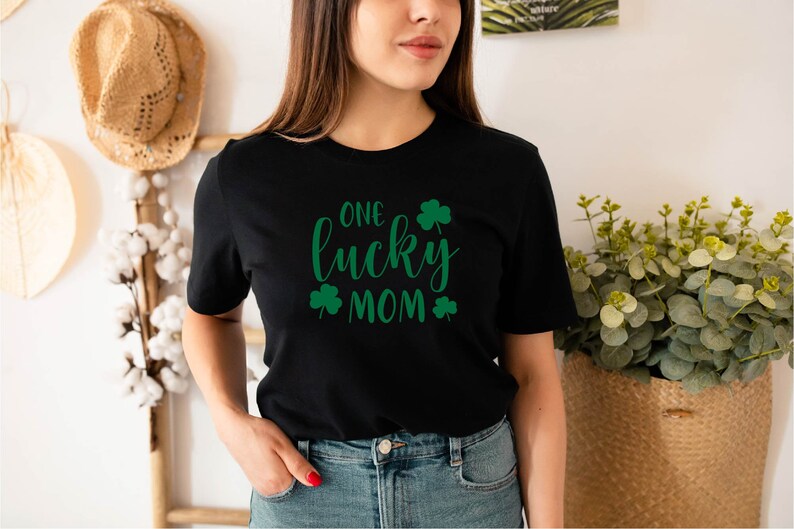 May include: Black t-shirt with the text "One lucky mom" in green cursive lettering and shamrock designs.