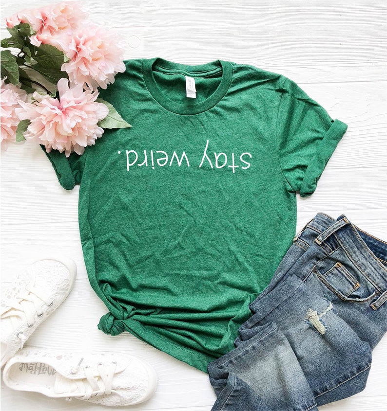 May include: Green t-shirt with the text "Stay Weird" in white lettering.
