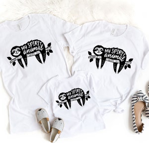 May include: Three white t-shirts with a black and white illustration of a sloth on a branch and the text "My Spirit Animal".