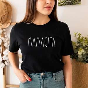 Może przedstawiać: Czarny t-shirt z nadrukiem "MAMACITA" w kolorze białym z przodu.