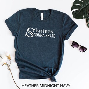 May include: A dark blue t-shirt with the text "Skaters Gonna Skate" in white lettering. The shirt is made of a soft, comfortable material and is perfect for everyday wear.