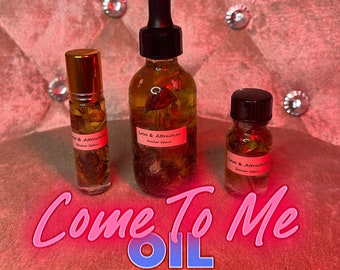 Könnte beinhalten: Drei Glasflaschen Öl mit einem rosa und roten Thema. Die Flaschen sind mit "Love & Attraction" und "Soular Space" beschriftet. Der Text "Come To Me Oil" wird in Pink und Blau angezeigt. Die Flaschen sind mit Kräutern und Blumen gefüllt.