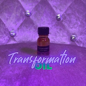 Könnte beinhalten: Eine kleine Glasflasche mit schwarzem Verschluss, gefüllt mit einer goldbraunen Flüssigkeit. Die Flasche hat ein Etikett mit der Aufschrift "Transformation, Soular Space". Das Bild ist vor einem violetten, getufteten Hintergrund mit dekorativen Kristallakzenten angeordnet, und die Worte "Transformation OIL" sind unten geschrieben.