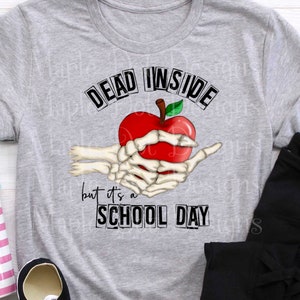May include: A gray t-shirt with the text "Dead Inside but it's a School Day" and a skeleton hand holding a red apple.