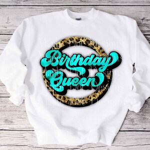 K&ouml;nnte beinhalten: Wei&szlig;er Pullover mit einem schwarzen Kreisdesign mit einem goldenen Leopardenmuster und dem Text "Birthday Queen" in T&uuml;rkis.