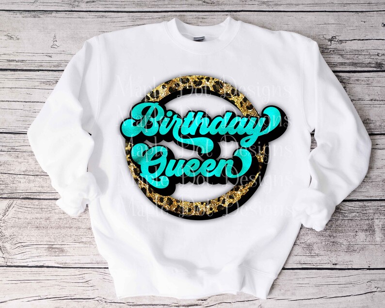 K&ouml;nnte beinhalten: Wei&szlig;er Pullover mit einem schwarzen Kreisdesign mit einem goldenen Leopardenmuster und dem Text "Birthday Queen" in T&uuml;rkis.