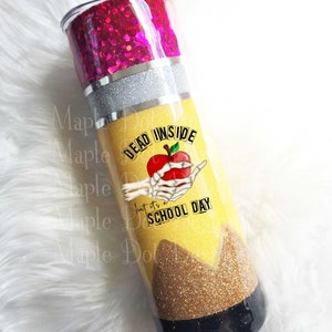 May include: A yellow and black glitter tumbler with a pencil design. The tumbler has a pink glitter lid and a skeleton hand holding a red apple with the text "Dead Inside but it's a School Day".