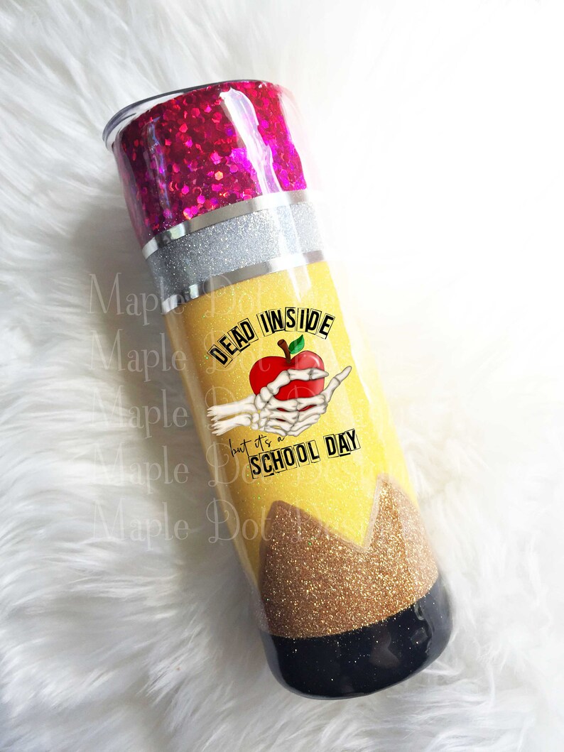 May include: A yellow and black glitter tumbler with a pencil design. The tumbler has a pink glitter lid and a skeleton hand holding a red apple with the text "Dead Inside but it's a School Day".