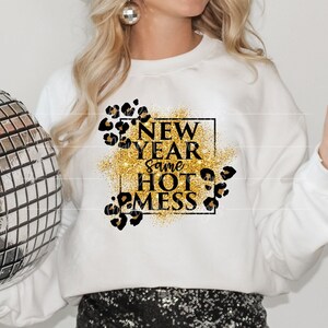 May include: White sweatshirt with gold glitter and black text that reads "New Year Same Hot Mess" with leopard print accents.